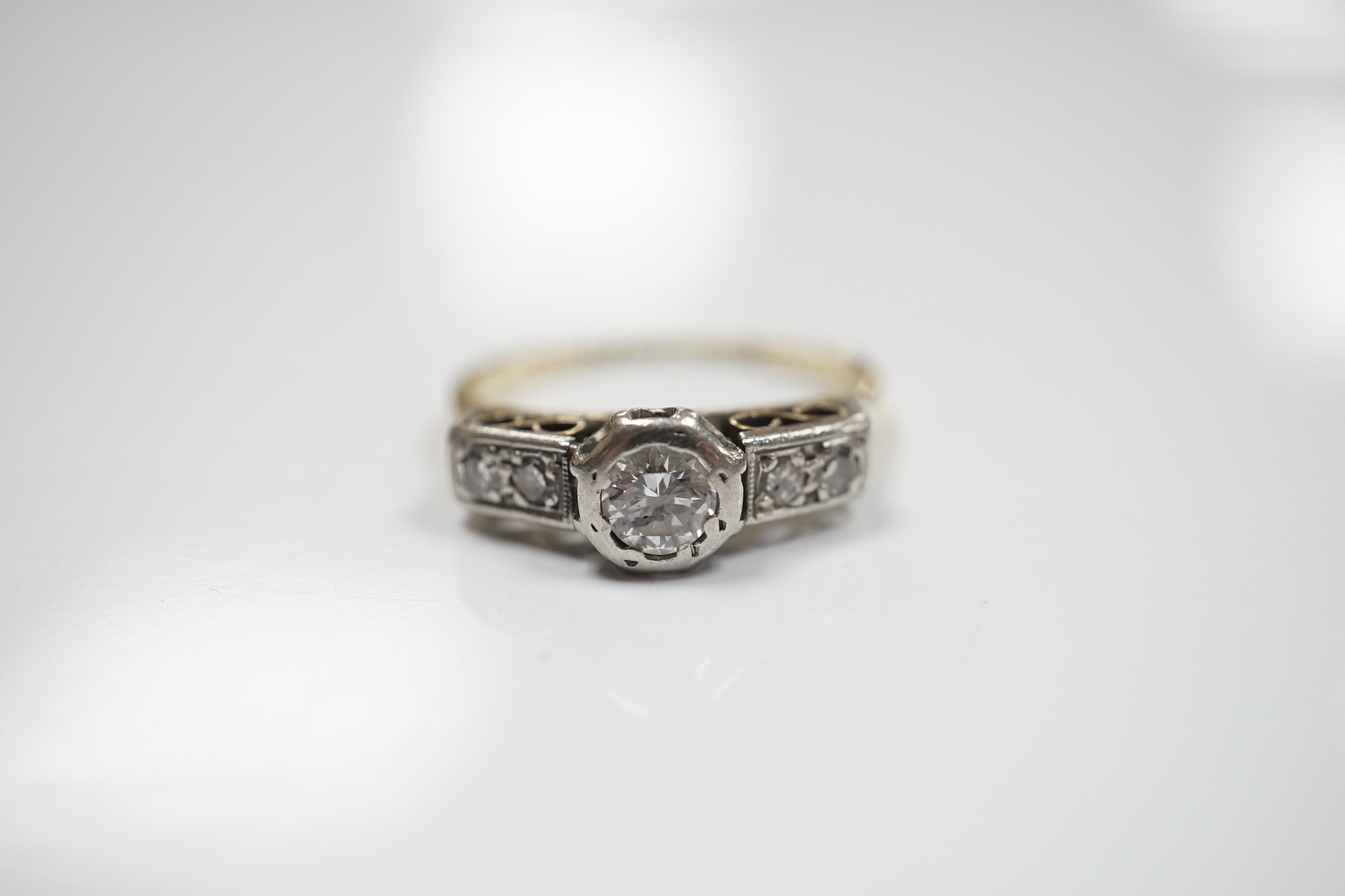 An 18ct, plat. and collet set single stone diamond ring, with four stone diamond set shoulders, size N/O, gross weight 3 grams. Condition - poor to fair